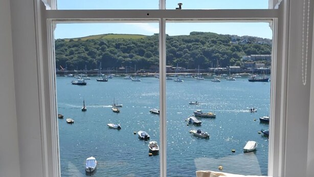 A view through a window of a marina with boats and a hilly landscape in the background. - 3 bedroom accommodation in Fowey (Fowey)