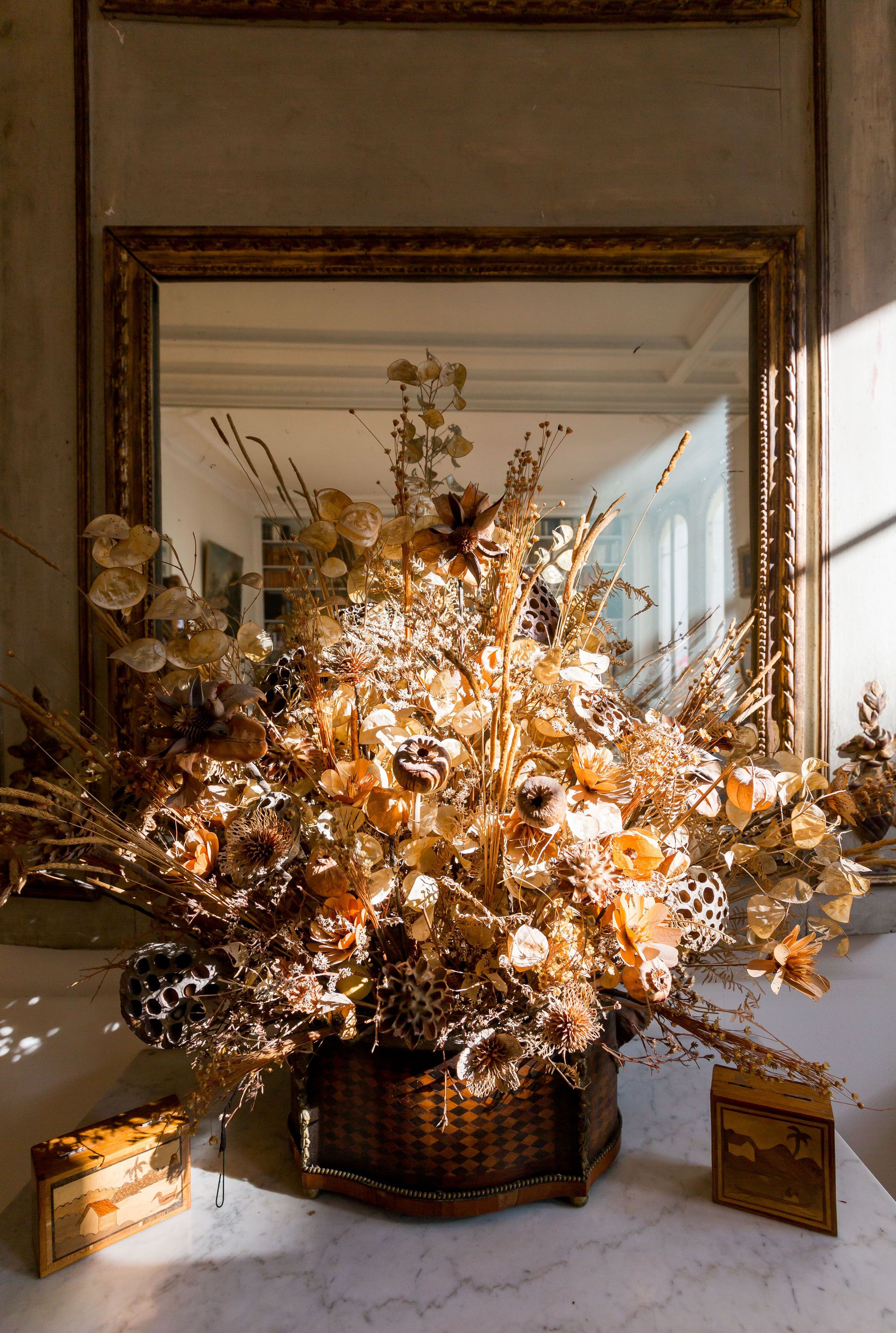 A mirror with a floral arrangement in front of it.