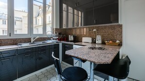 Eine moderne Küche mit dunklen Schränken, einer Granitarbeitsplatte und einem Fenster, das für natürliches Licht sorgt.