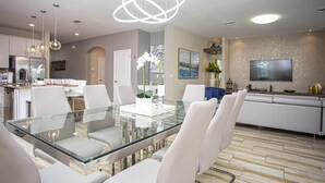 A modern kitchen with a glass dining table, white chairs, and a stainless steel refrigerator. - 4764- Great Family Home near Disney, Pool & Spa - Storey Lake Resort (Kissimmee)
