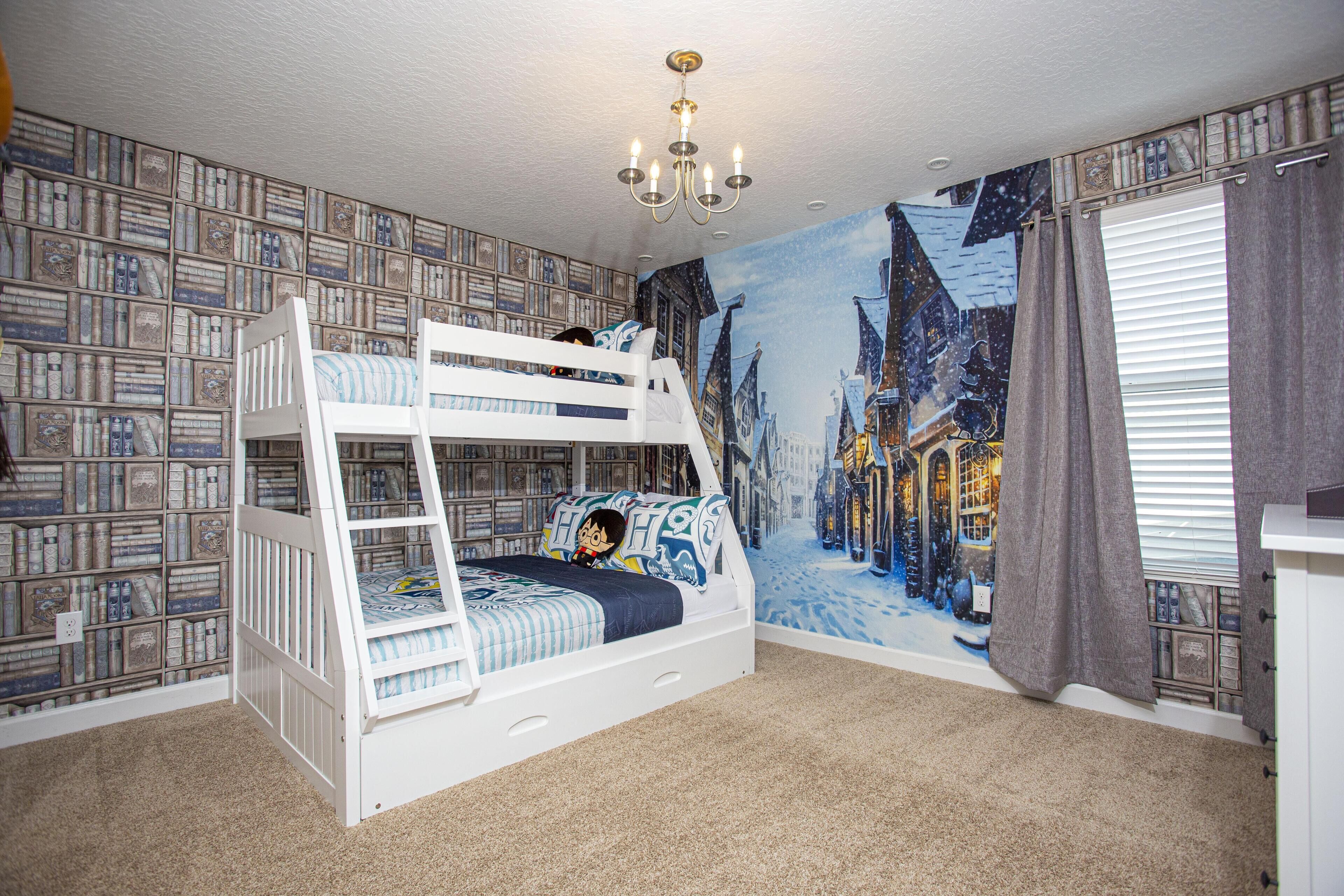 A bunk bed room with a cityscape mural, a chandelier, and a bookshelf wall.
