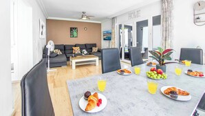 Ein Essbereich mit Tisch, gedeckt für das Frühstück, einschließlich Croissants, Muffins und Obst.