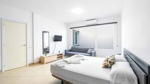 Ein modernes Hotelzimmer mit einem großen Bett, einem Flachbildfernseher, einer Couch und einem Fenster mit Blick.