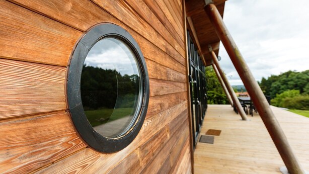 A wooden exterior wall with a circular window.