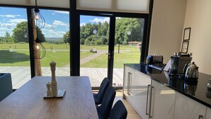 A modern kitchen with a large window, a wooden dining table, and blue chairs.