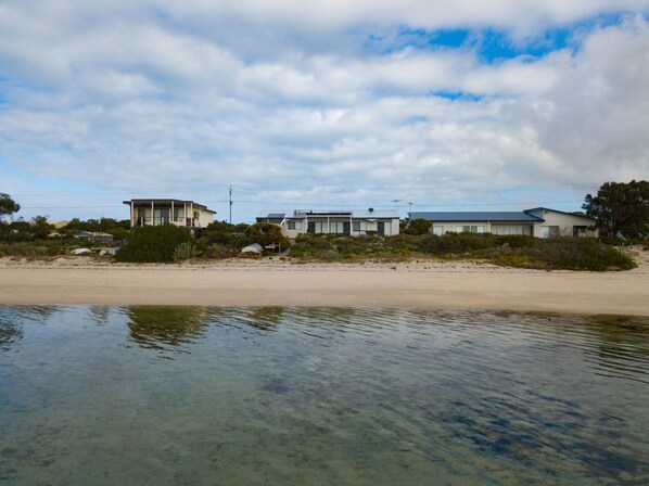 Une propriété située en bord de mer, avec des maisons modernes, une eau cristalline et une plage de sable.