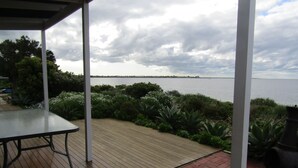 Un espace extérieur abrité doté d’une terrasse en bois, d’un chemin en briques et d’une vue sur la mer.