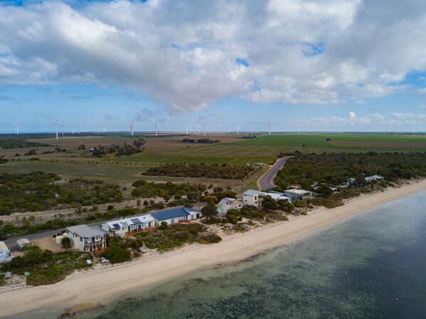 A coastal area with a beach, a road, and wind turbines in the distance.