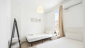 Hotelkamer met twee bedden, een staande lamp, een raam met gordijnen en een wandairconditioner.