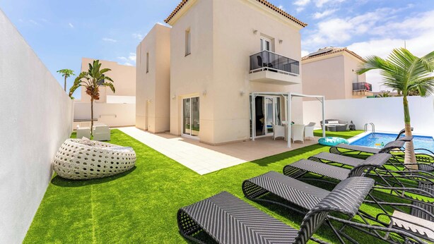 Een modern huis met een zwembad, balkon en een verzorgd gazon.