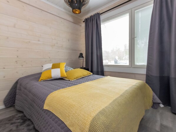 A bedroom with a bed, a lamp, and a window with curtains.