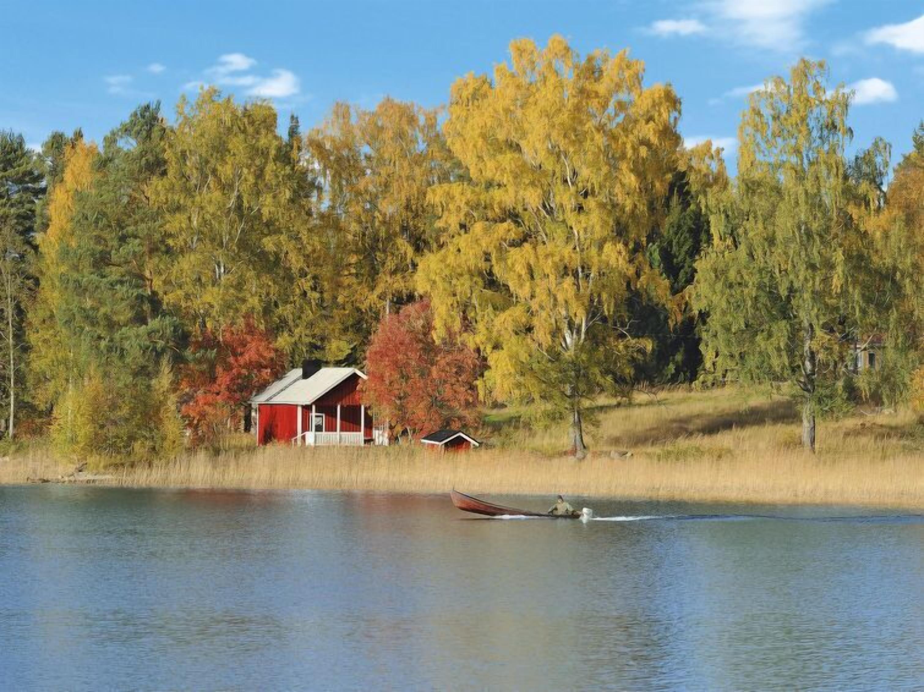 Un chalet au bord du lac, avec un quai et un petit bateau.