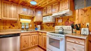 A kitchen with wooden cabinets, a stainless steel dishwasher, a white stove, and a microwave.