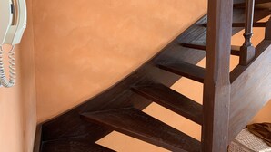 A wooden staircase with a handrail, a wall-mounted telephone, and a textured orange wall. - Duplex T2 Arcachon: Terrasse, Wifi, 100m Plage, Proche Centre (Arcachon)