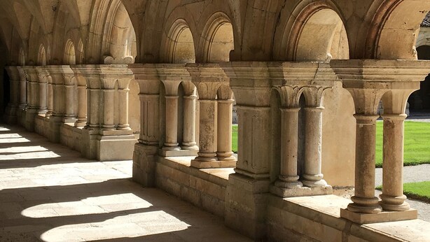 Une série d’arches en pierre soutenues par des colonnes, qui font probablement partie d’un bâtiment ou d’une structure historique.