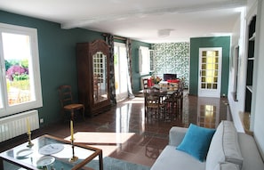 Ein geräumiges Wohnzimmer mit Essbereich, großen Fenstern und Blick ins Freie.