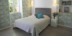 A bedroom with a bed, nightstands, a bookshelf, and a window.