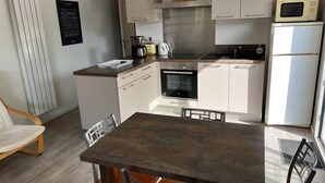 A compact kitchen with a central island, a microwave, a stove, and a refrigerator.