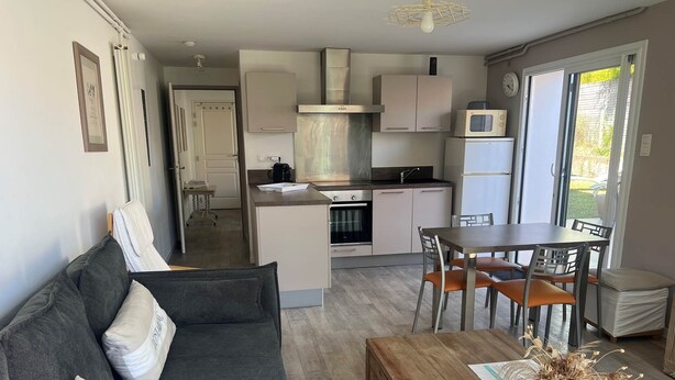 A modern kitchen with white cabinets, a microwave, and a stove. There is a dining area with a wooden table and chairs.