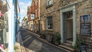 A narrow street lined with traditional stone buildings, including a tea room with a sign indicating it is open. - 2 bedroom accommodation in Fowey (Fowey)