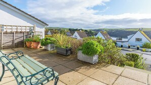 A patio with a bench, potted plants, and a view of houses and hills. - 2 bedroom accommodation in Fowey (Fowey)