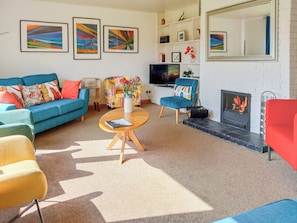 A living room with a sofa, armchairs, a coffee table, a fireplace, and artwork on the walls.
