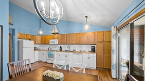 A modern kitchen with wooden cabinets, a white refrigerator, and a dining area with a wooden table and chairs.