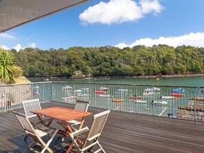 Une terrasse en bois avec une table et des chaises, donnant sur une marina où sont amarrés différents types de bateaux.