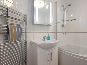 A modern bathroom with a glass shower enclosure, a white sink with a soap dispenser, and a towel rack with striped towels.