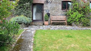 A stone cottage with a small garden, a bench, and a potted plant. - 2 bedroom accommodation in Fowey (Fowey)