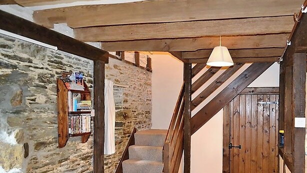 A staircase with stone walls and wooden beams, leading to a door. - 2 bedroom accommodation in Fowey (Fowey)