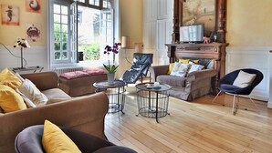 Un salon spacieux avec un haut plafond, une cheminée et une grande fenêtre.