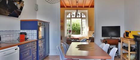 A modern kitchen with a dining area, featuring a wooden table, chairs, and a built-in oven.