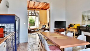 Une cuisine moderne avec un coin repas, comprenant une grande table, des chaises et un téléviseur.