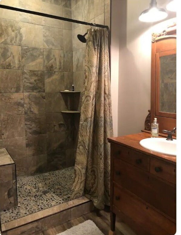 Un bagno con doccia, un lavabo con specchio e un lavandino.