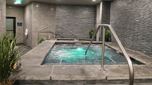 A spa area with a hot tub, metal railings, and a stone wall. - The Premier Ski-in Ski-out Address in all of Colorado - Unit LIcense 81047001. (Breckenridge)