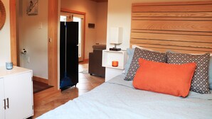 A bedroom with a bed, pillows, a nightstand, a lamp, and a wardrobe. - Sunset Cottage with Beautiful Blue Ridge Mountain Views (Clyde)