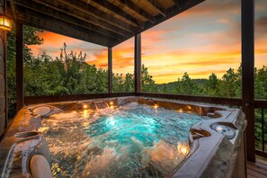 A hot tub with a wooden deck and a view of a sunset. - Blackberry Lodge- Pet Friendly | Outdoor Firepit | Hot Tub (Blue Ridge)