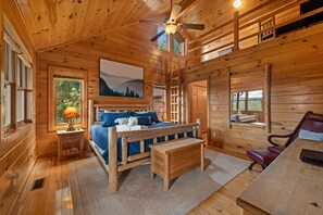 A wooden cabin interior with a bed, a desk, and a chair. - Blackberry Lodge- Pet Friendly | Outdoor Firepit | Hot Tub (Blue Ridge)