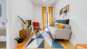 Una sala moderna con un sofá, una mesa de centro y un televisor. Hay una planta sobre la mesa de centro y otra planta en el suelo.