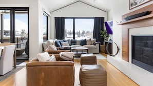 Ein modernes Wohnzimmer mit Kamin, großen Fenstern und einer gemütlichen Sitzecke.