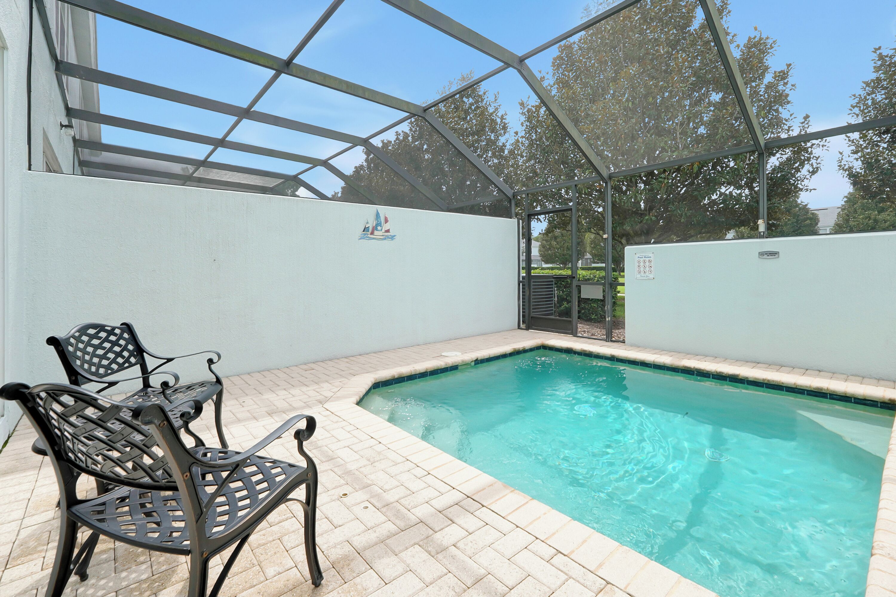 A covered outdoor swimming pool with a patio area and metal chairs.