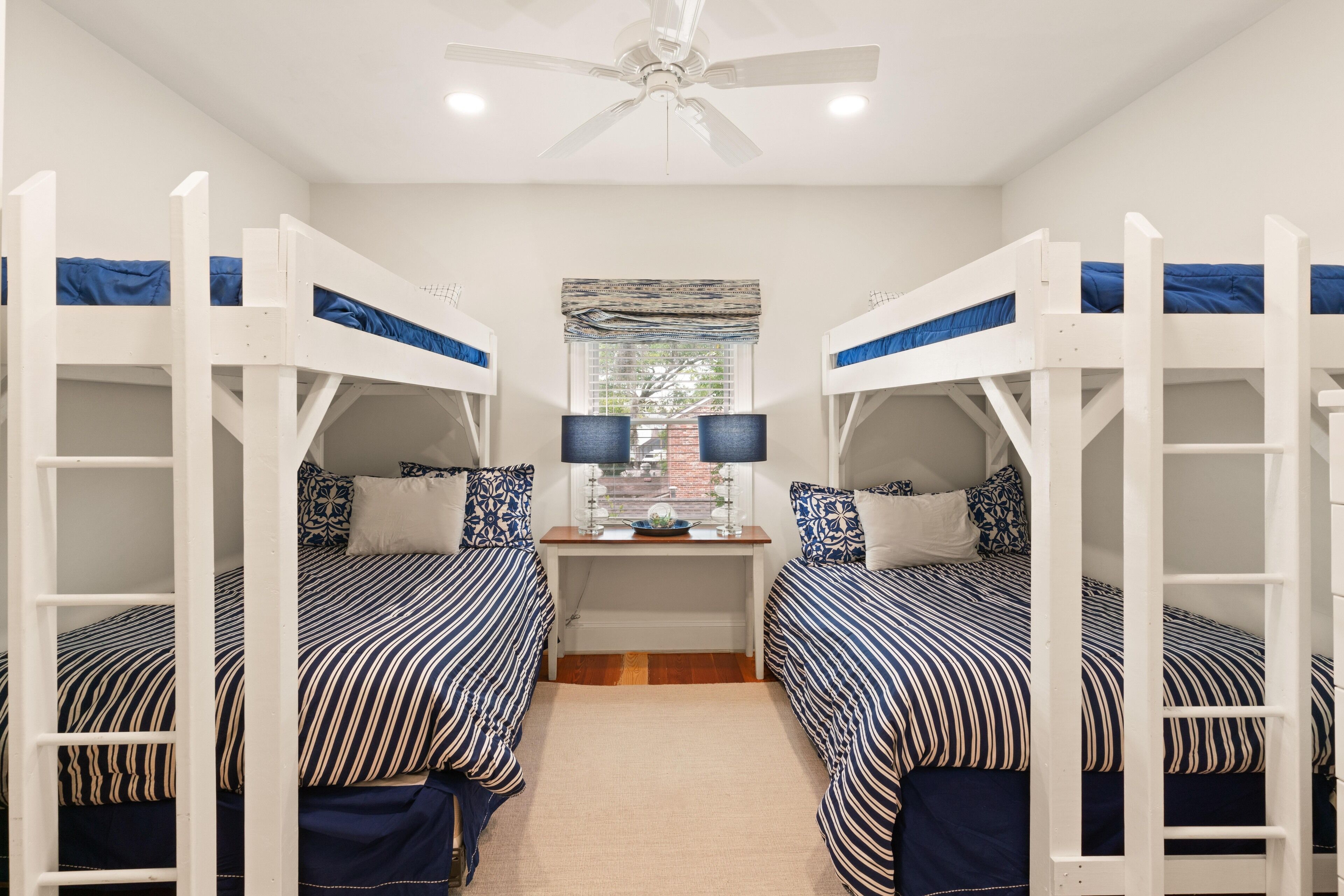 A room with bunk beds, a desk, and a ceiling fan.