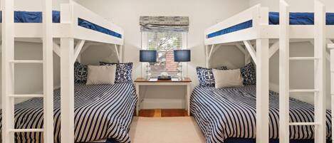A room with bunk beds, a desk, and a ceiling fan.