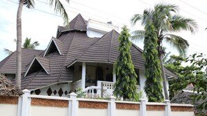 A house with a steeply pitched roof, a balcony, and a white fence. - A wonderful Beach property in Diani Beach Kenya,a dream holiday place (Mombasa)
