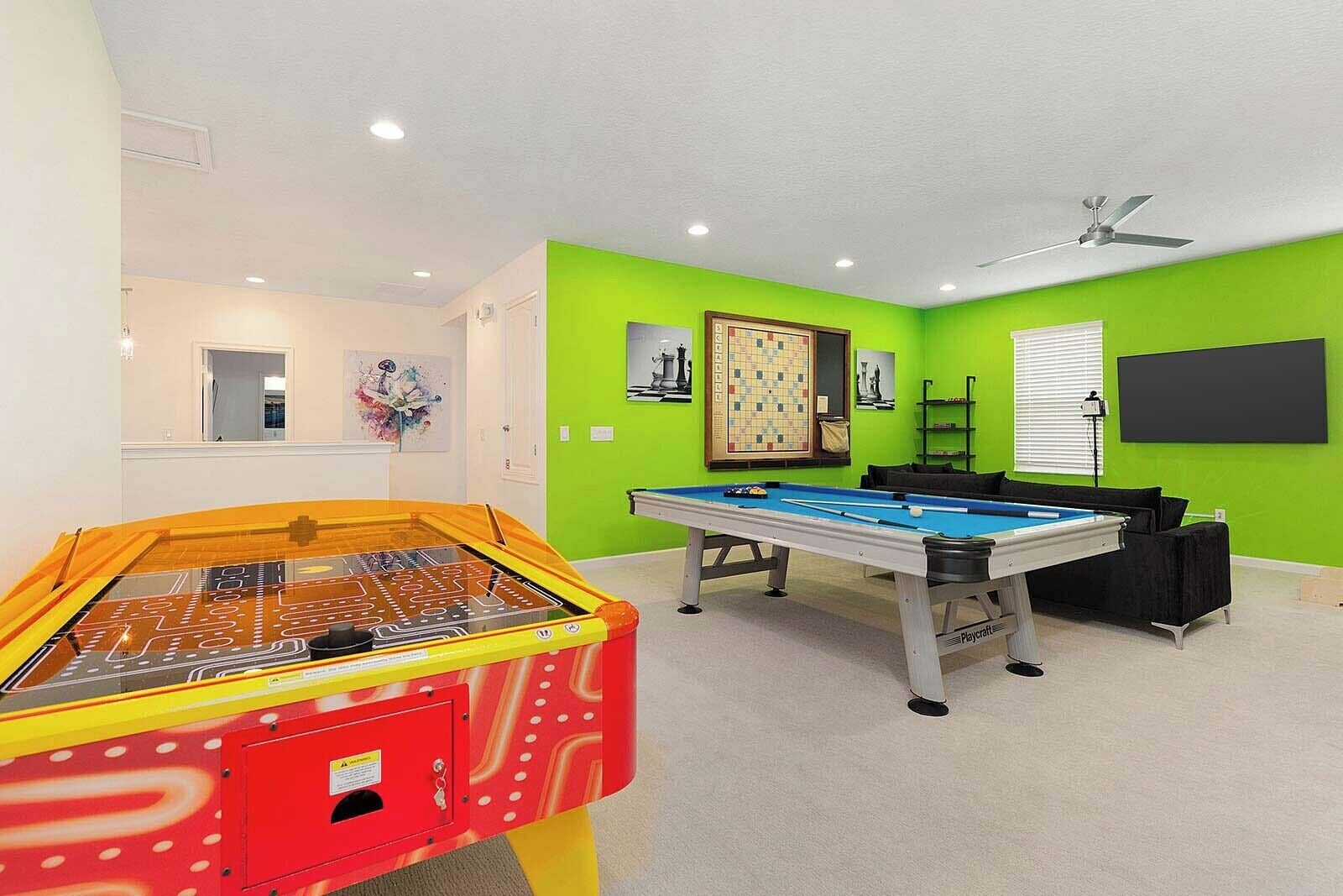 Une pièce équipée d’une table de billard, d’un baby-foot et d’un ventilateur de plafond.
