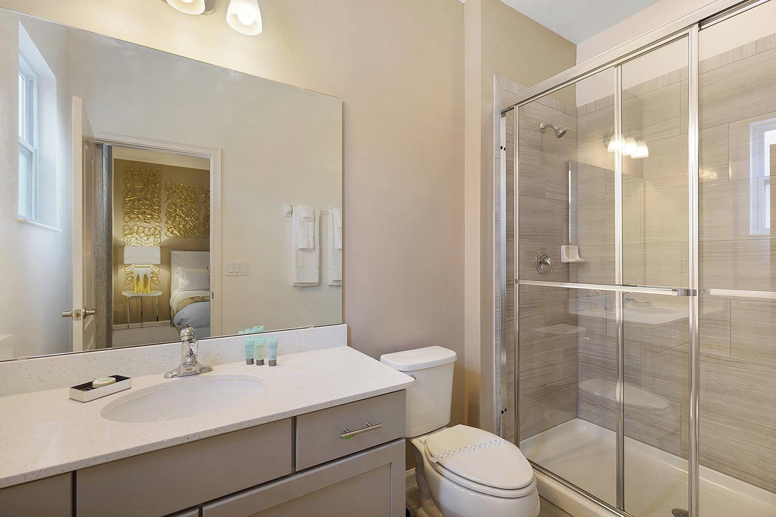 A modern bathroom with a glass shower enclosure, a large mirror, and a white sink.