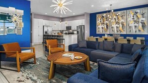 Una sala moderna con una pared azul decorativa, un comedor y una cocina.