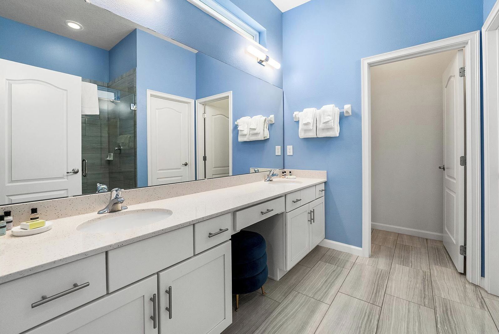 Un baño moderno con tocador doble, un espejo grande y ducha a ras de suelo.