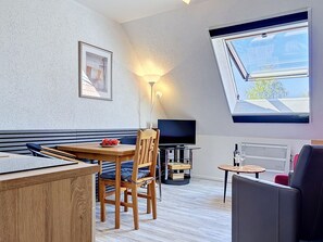 A modern room with a wooden dining table, a sofa, a TV, and a skylight. - Gollwitzer Park (Insel Poel) by Interhome (Gollwitz (Insel Poel))